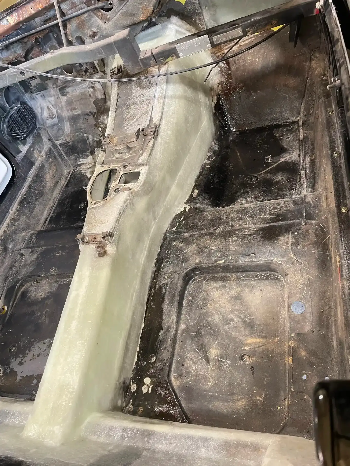 Bare floor pan with console tunnel during restoration